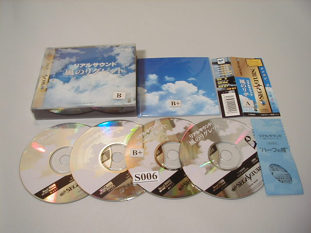 Contents of Sega Saturn Box, showing 4 cd's, a 4- cd tray, a booklet and a bag with seeds.